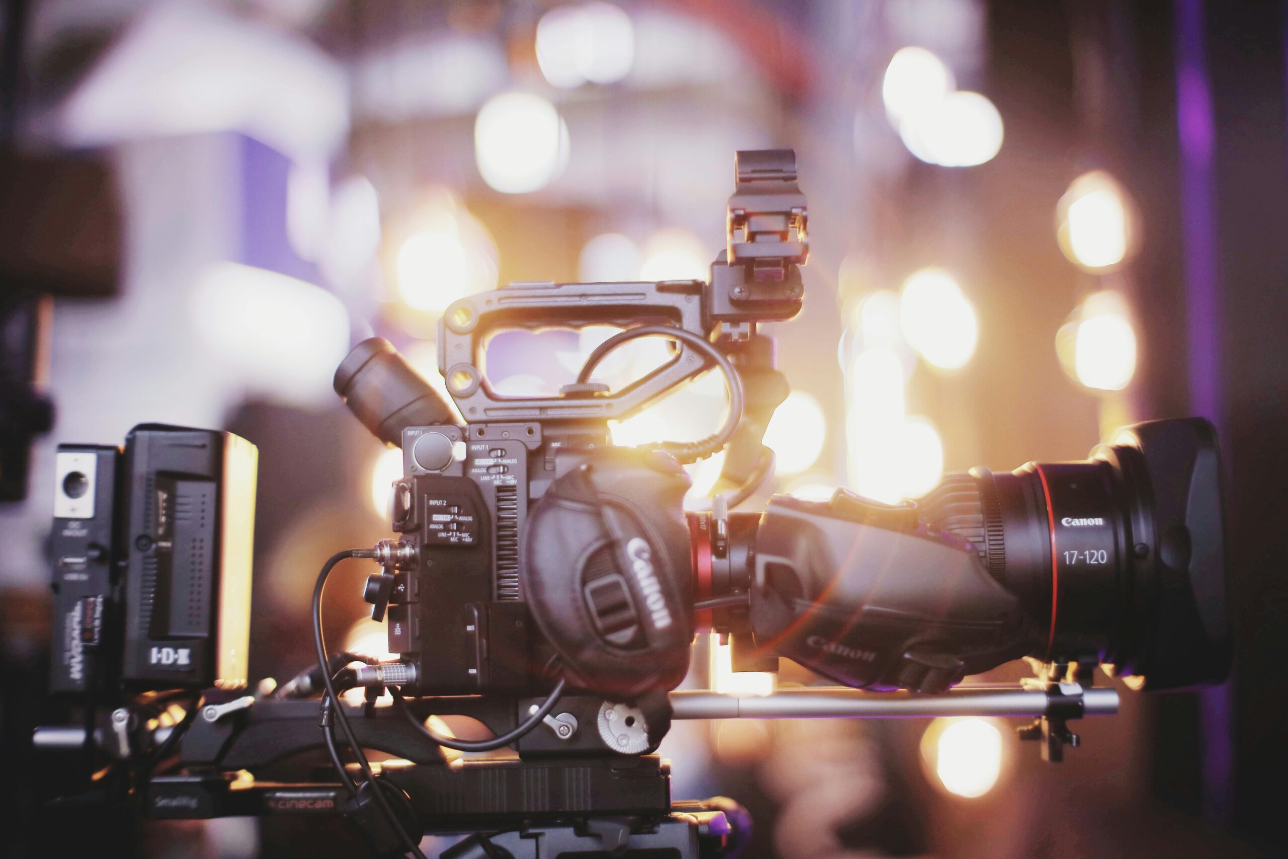 Close-up of professional video camera setup for studio filming with blurred lights in the background.