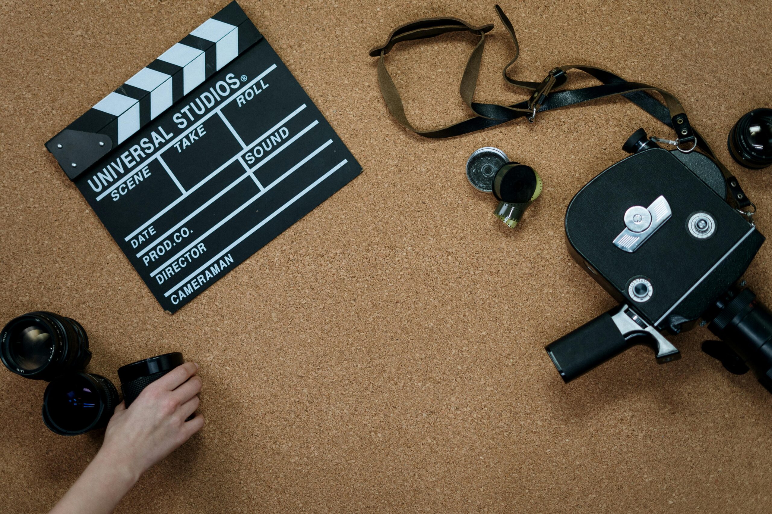 Flat lay of vintage film equipment and clapperboard on corkboard. Ideal for cinema and filmmaking concepts.